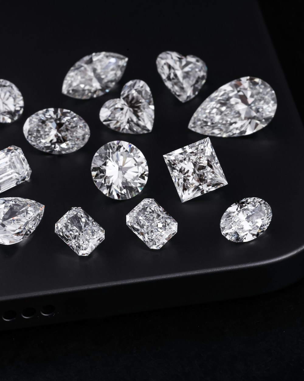 Loose diamonds in round, pear, heart, princess and radiant cuts on a black tray